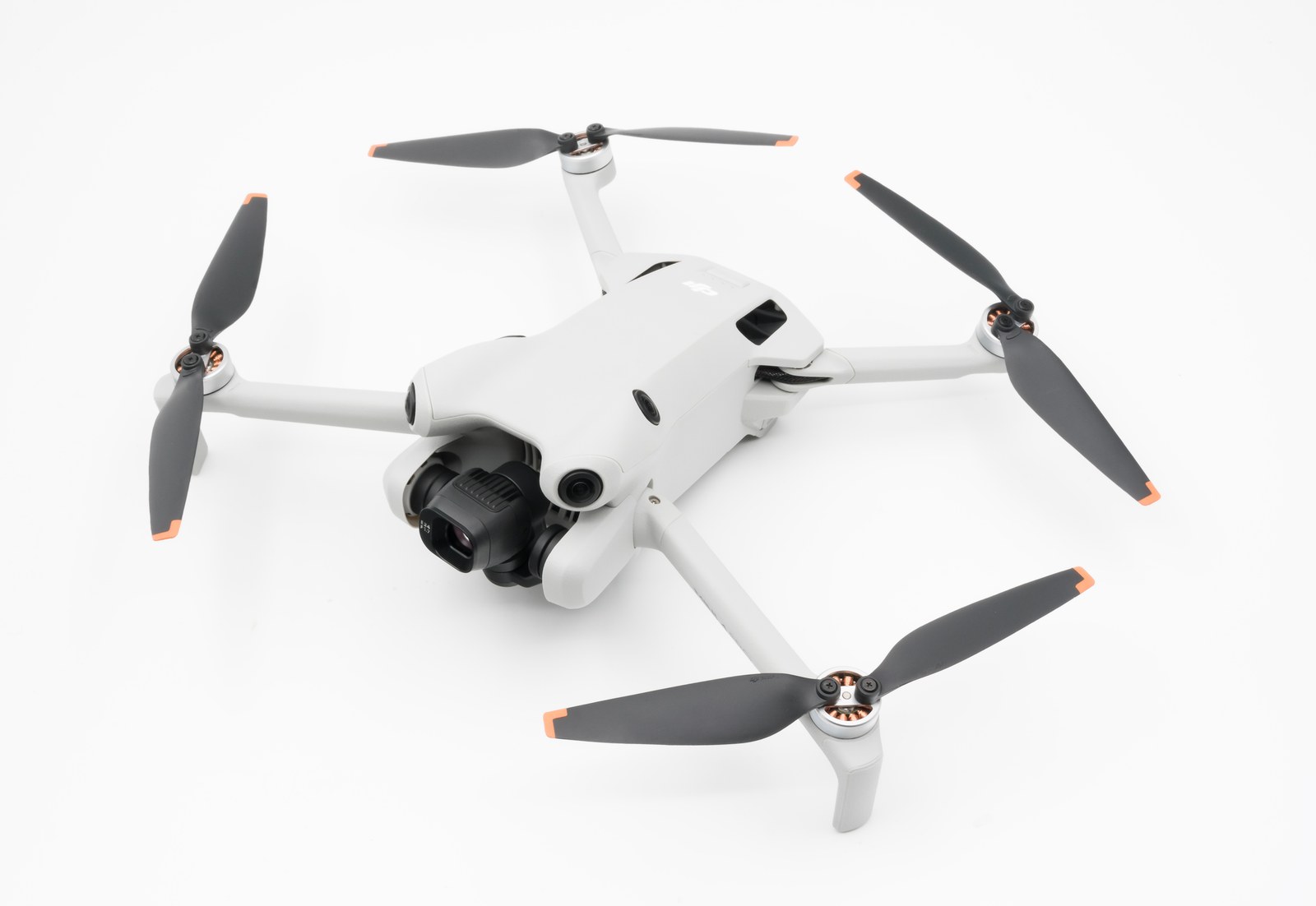 DJI Mini 4 Pro drone unfolded on a white background, gimbal camera and omnidirectional sensors visible