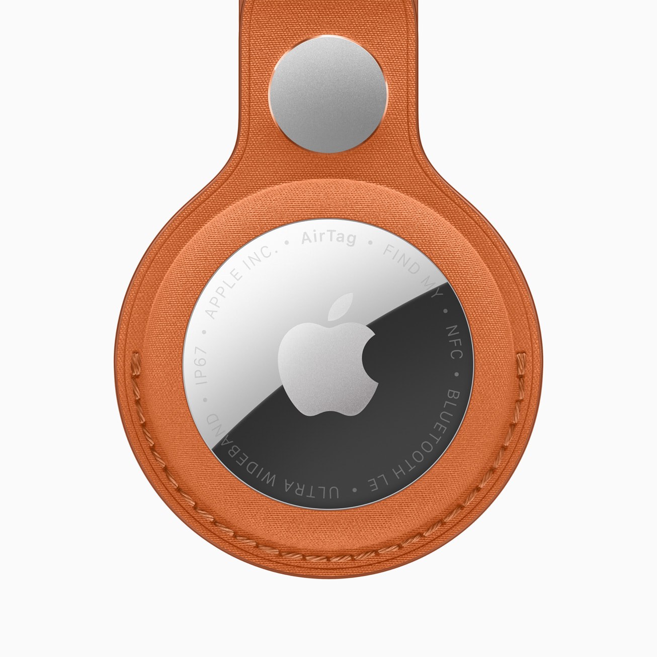 The second-generation Apple AirTag seated in an orange FineWoven key ring, seen from the back with the Apple logo