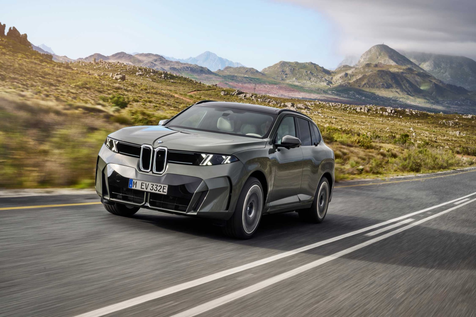 The new BMW iX5 driving on a mountain road, front three-quarter view