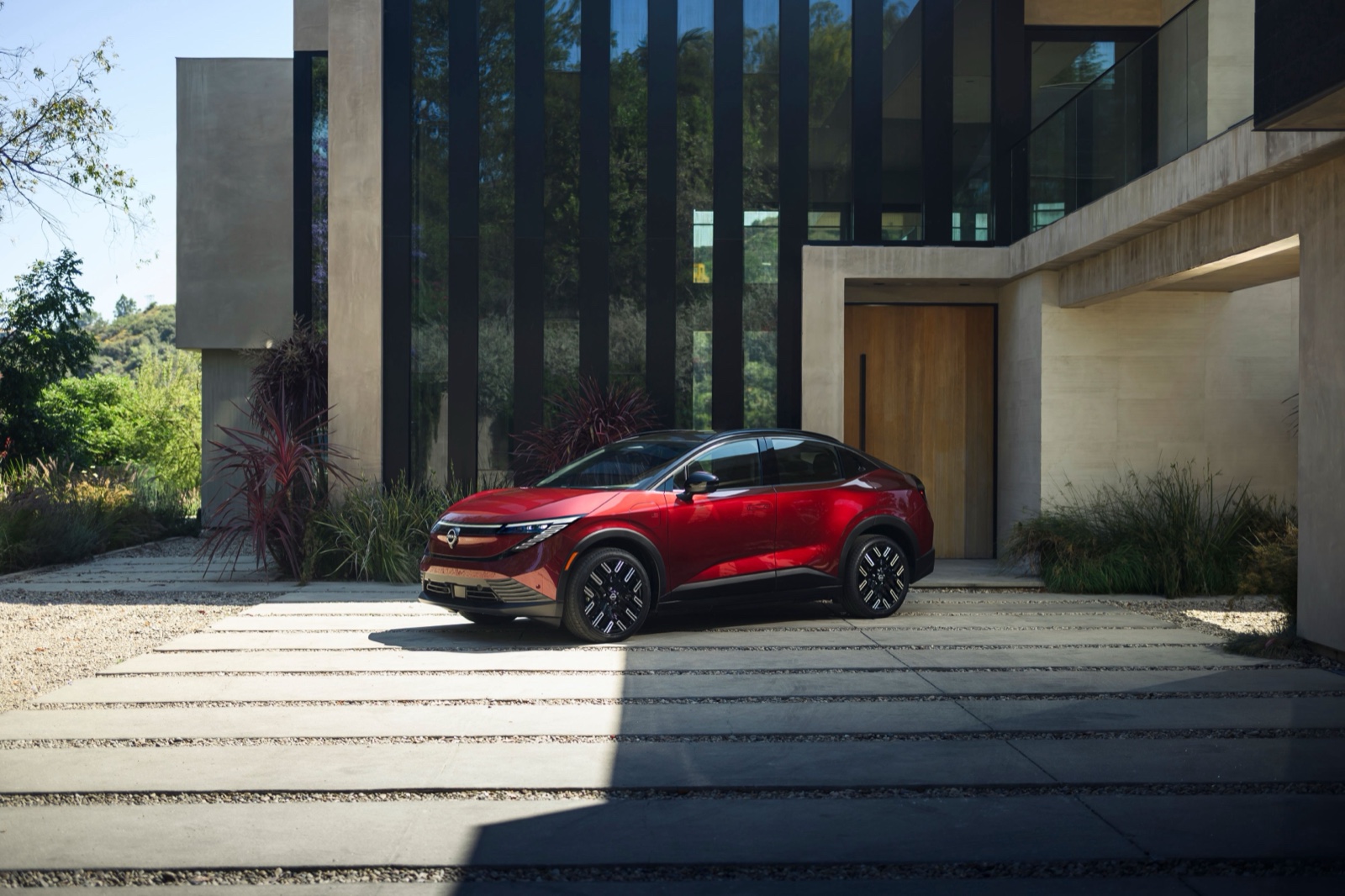 Red 2026 Nissan Leaf parked outside a modern house, front three-quarter view